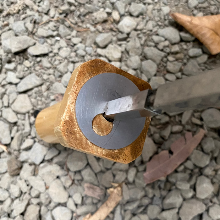 Tool with a wooden handle and metal blade on a gravel surface