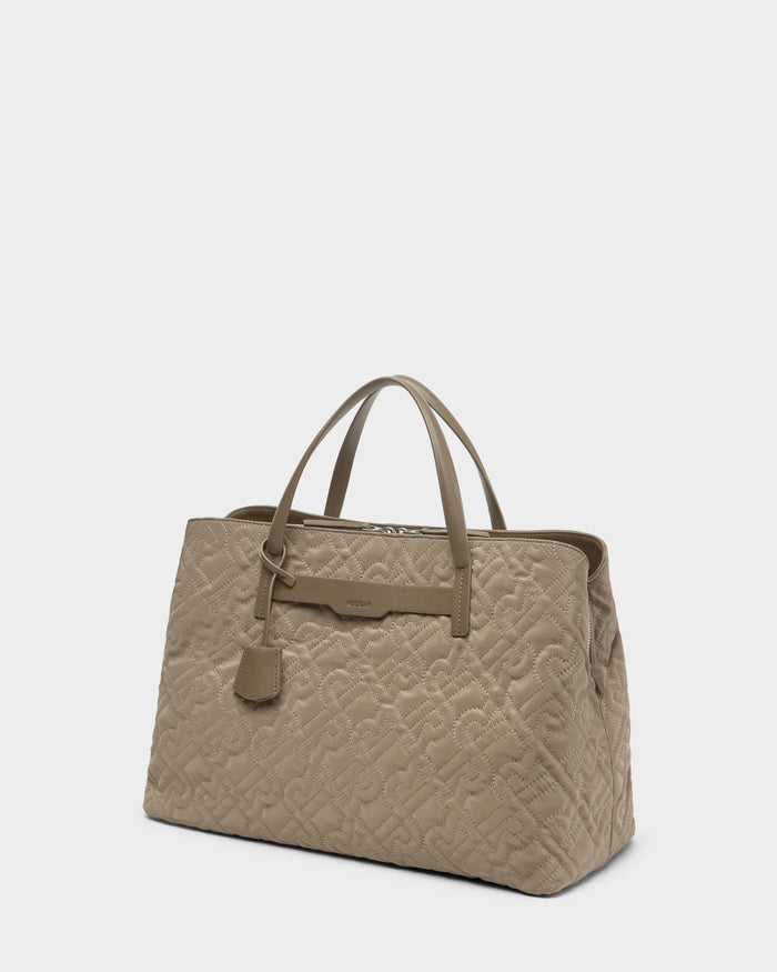 The Rudsak ASMINE - L325005 Almond tote is a beige quilted monogram bag with two top handles, subtle embossed pattern, and a small tag—an elegant accessory for any occasion, shown on a plain white background.