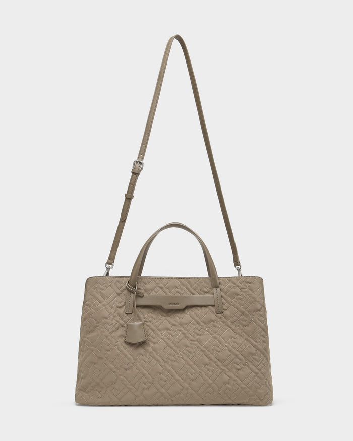 The ASMINE - L325005 Almond by Rudsak is a taupe quilted monogram tote with two top handles, a detachable adjustable shoulder strap, and a hanging tag. This elegant bag is displayed against a plain white background.