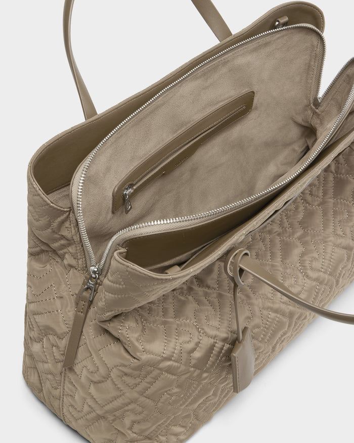 The ASMINE - L325005 Almond by Rudsak is a beige quilted monogram tote with an open top, suede-lined spacious interior, zippered pocket, and leather tag—an elegant choice for everyday style.