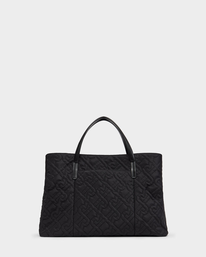 The Rudsak ASMINE - L325005 Black tote is a large black quilted bag with embossed interlocking letters and two black leather handles, shown against a plain light background.