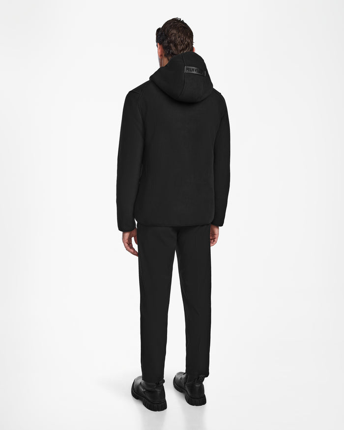 A person stands with their back to the camera, wearing the Rudsak BILLY - U524501 Black M, paired with black pants and shoes against a white background—ideal casual winter wear.
