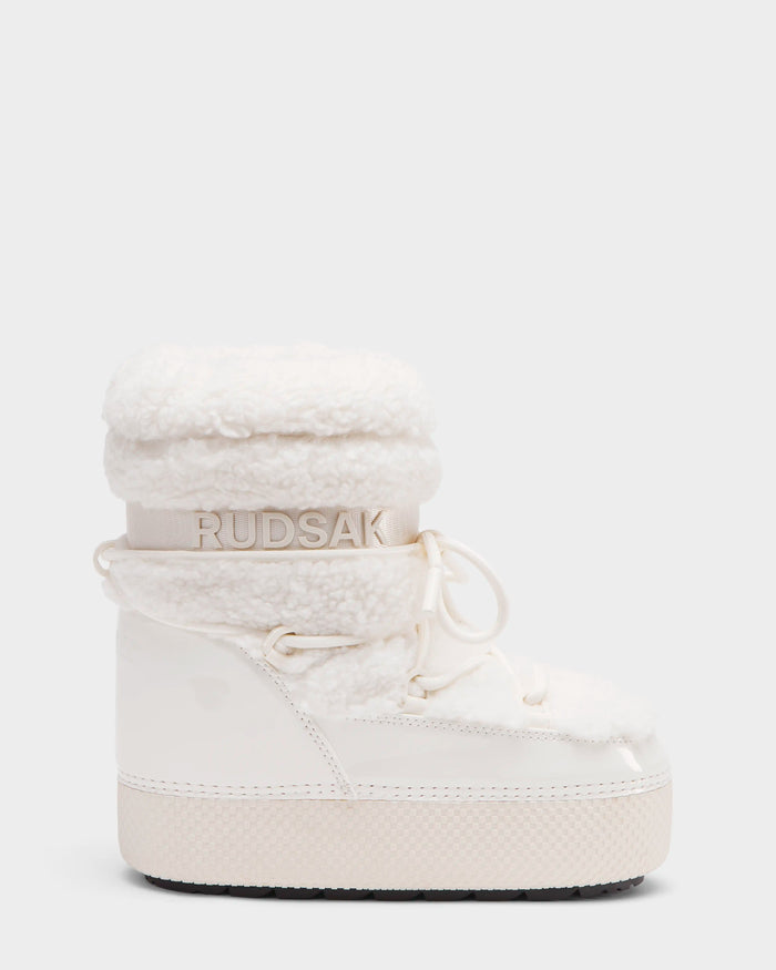 The Rudsak KATHY Y - 1224500 Iceland is a white winter boot with a thick sole, fluffy fleece collar, water-repellent patent leather, lace-up front, and RUDSAK branding on an elastic ankle band, inspired by classic moon boots.