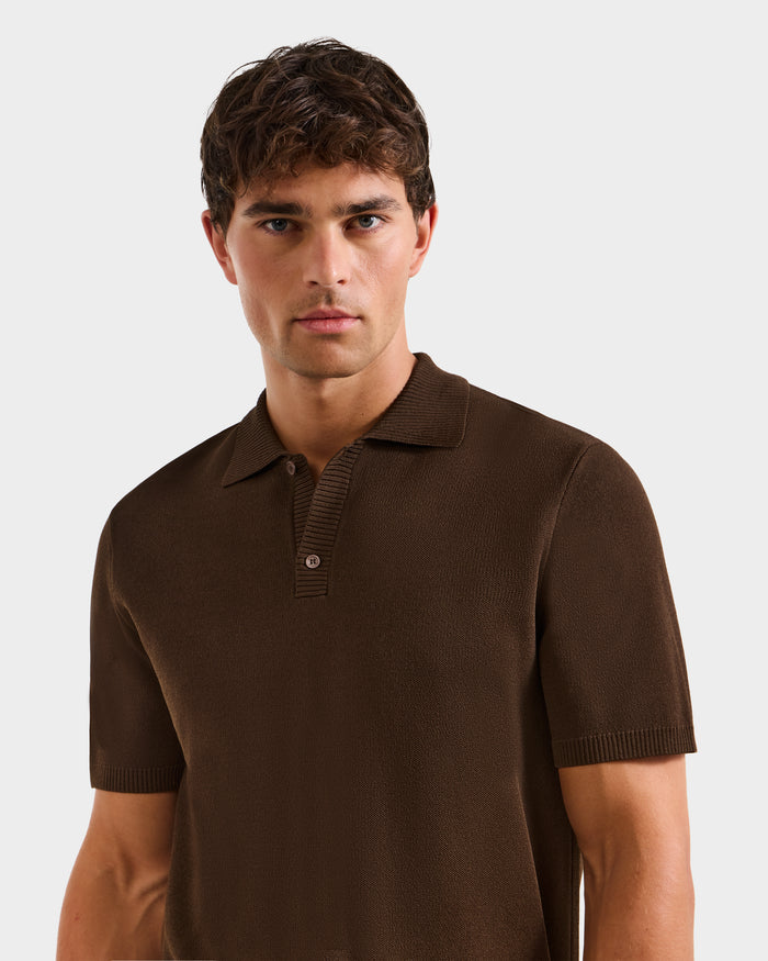 A young man with short brown hair wears the Rudsak MAISEN - 6524518 Mocha men's knit polo, looking directly at the camera and highlighting this modern wardrobe staple against a plain light gray background.
