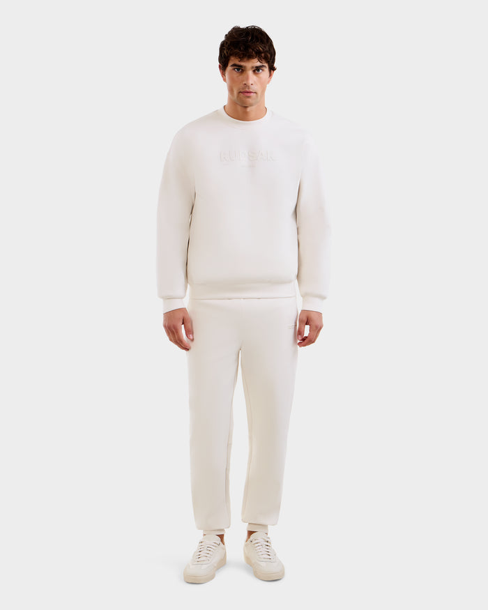 A man stands facing forward in the Rudsak MAXTON - U525007 Vanilla M cotton-blend jogger and sweatshirt with white sneakers, set against a plain white background for everyday comfort.