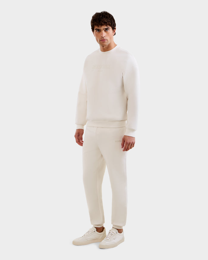 A man stands facing forward in a Vanilla M MAXTON sweatshirt by Rudsak, styled with matching joggers and sneakers against a plain white background.