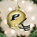 A gold football helmet Christmas ornament with a black P logo, hanging from a tree with green branches and white lights blurred in the background.