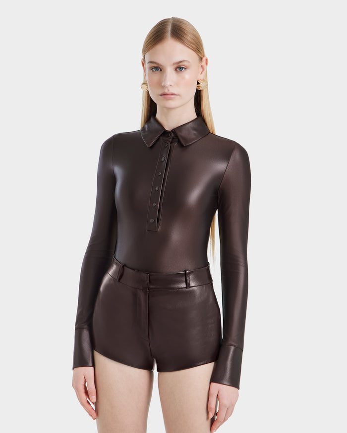 A woman with long, straight blonde hair models the Rudsak SHELLY - 8524537 Espresso fitted bodysuit and matching high-waisted shorts against a plain white background, looking forward with a neutral expression.