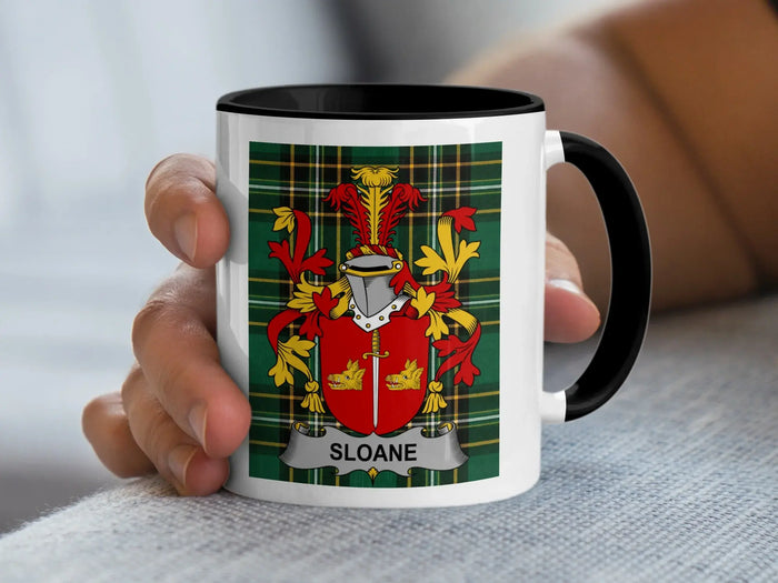 White mug with black rim, featuring a green tartan pattern and the Sloane family crest.