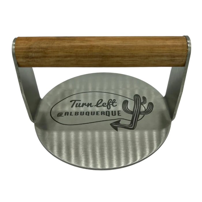 Stainless burger smasher with Turn Left at Albuquerque logo and wooden handle