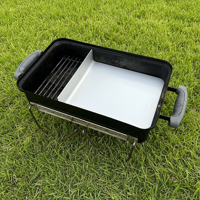 Stainless offset plate fitted into a Weber Go Anywhere showing the direct and indirect zones on a grass lawn