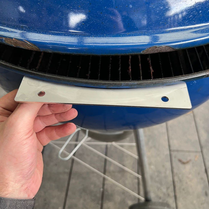 Mounting bracket held against a blue weber kettle