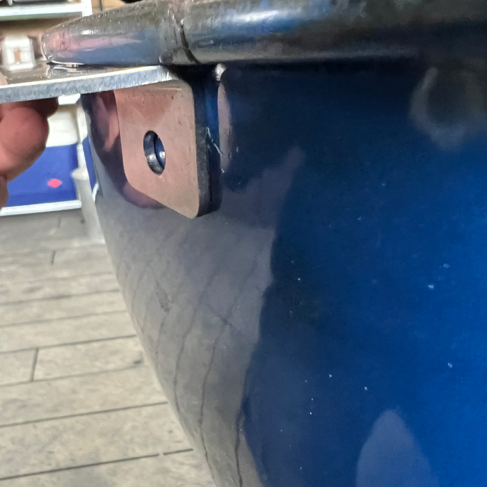 side view of a weber mounting bracket against a blue weber kettle